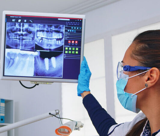 Dentist doctor and patient looking at digital teeh x-ray in dental office, person pov. Stomatology wearing protective face mask and gloves pointing at teeth radiography in stomatological clinic